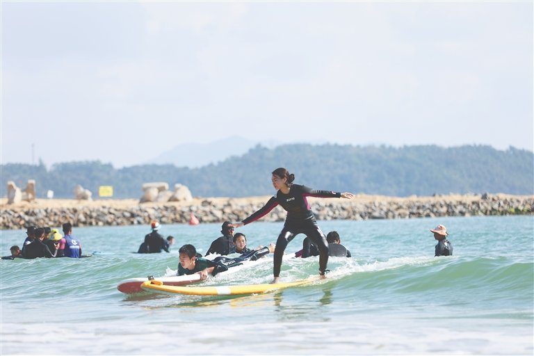 游客在万宁日月湾体验冲浪